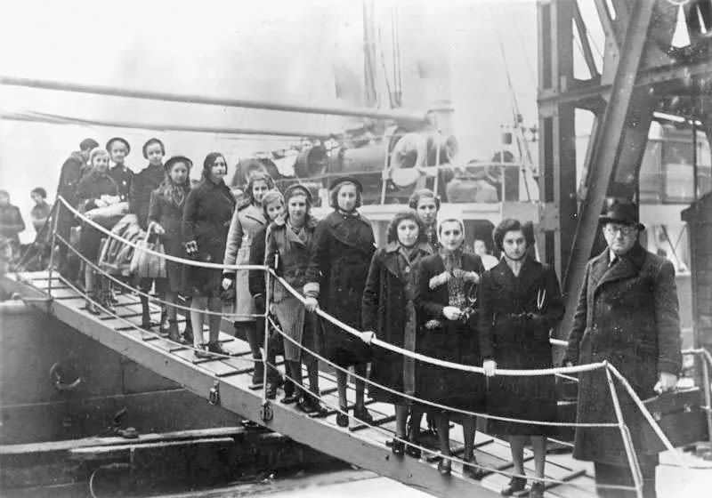 A black and white image showing a group of Jewish children disembark a boat in the UK which has arrived as part of the Kindertransport
