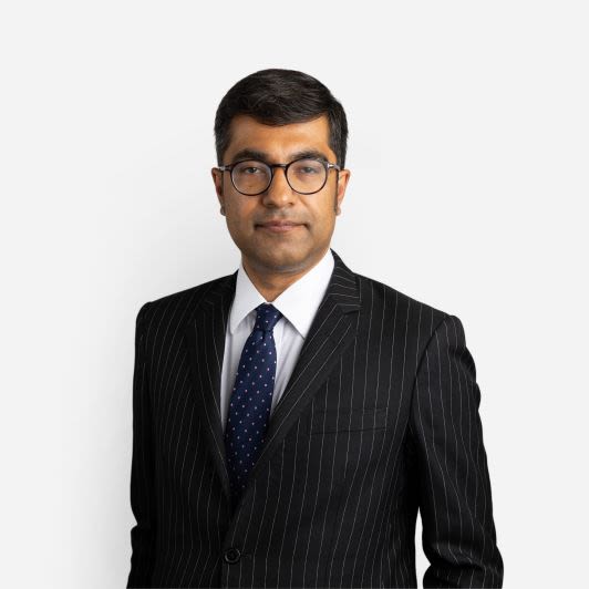 Ravi Aswani, a UCL alumni mentor, wearing a dark pinstripe suit and blue tie