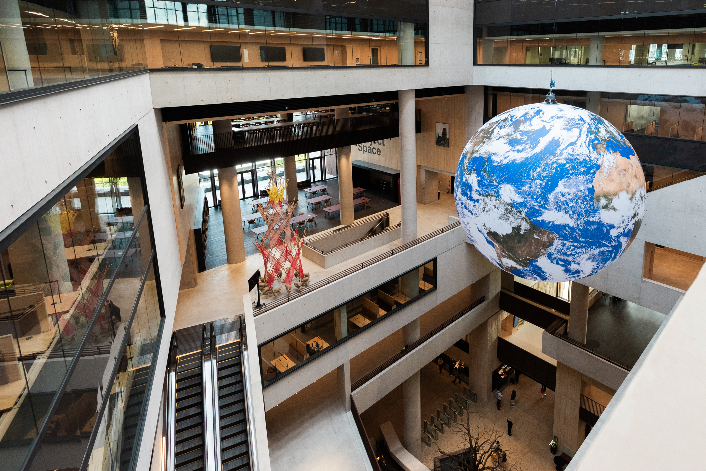 A large artwork of the Earth, hanging from the central atrium of UCL's Marshgate Building.